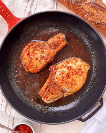 свінина у медово-гірчичному соусі подана на червоній пательні з багетом