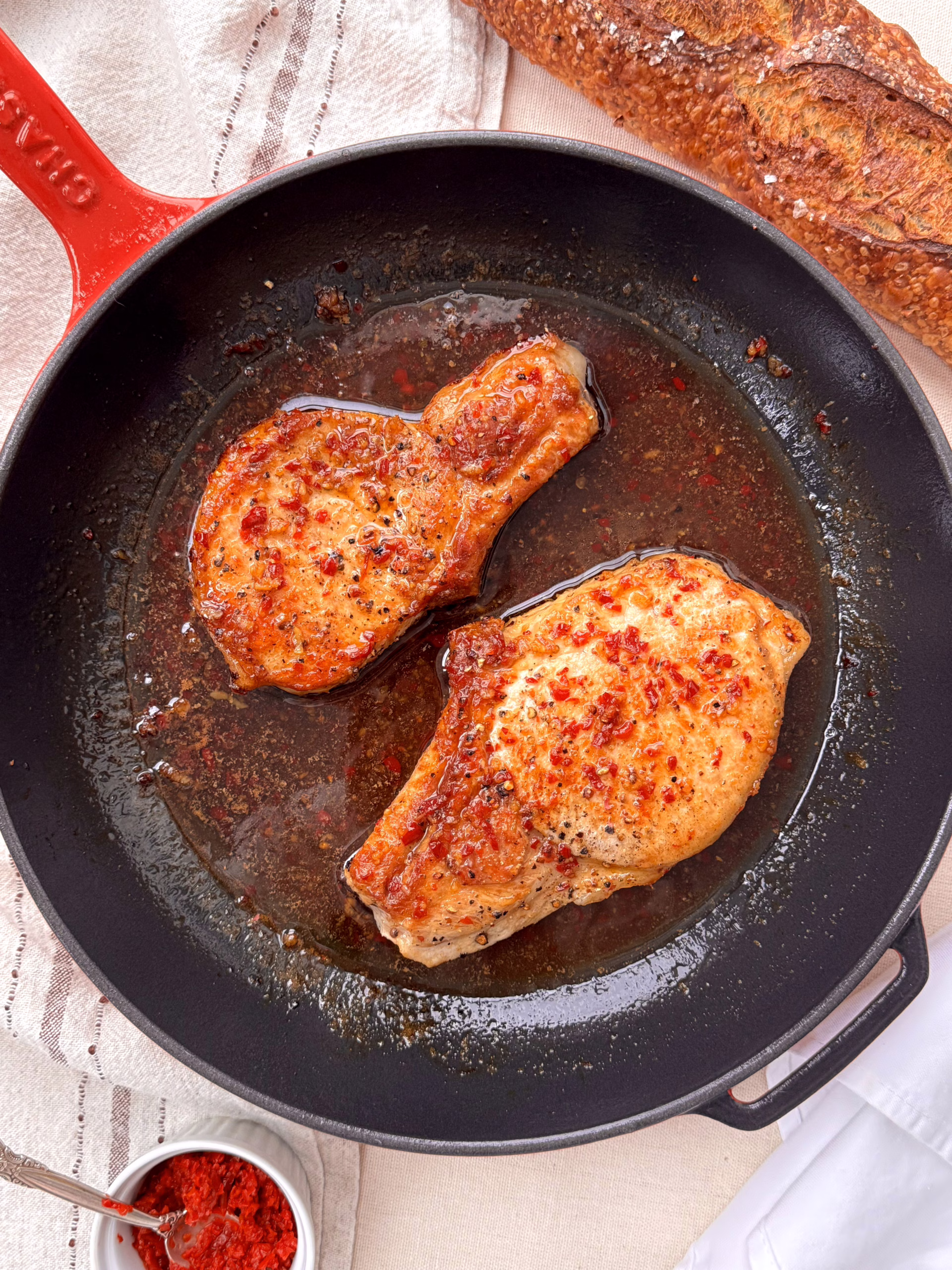 свінина у медово-гірчичному соусі подана на червоній пательні з багетом