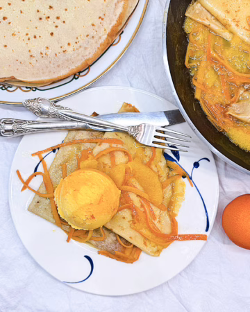 Легендарні ароматні млинці Креп сюзетт. Подані з кулькою морозива та апельсиновим соусом.