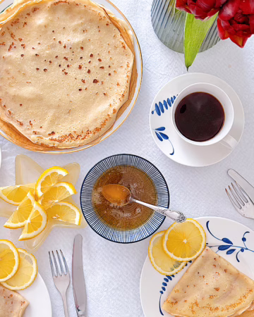 Тонкі французькі млинці на пиві, складені трикутниками на керамічній тарілці, щедро политі свіжим лимонним соком і посипані цукром.