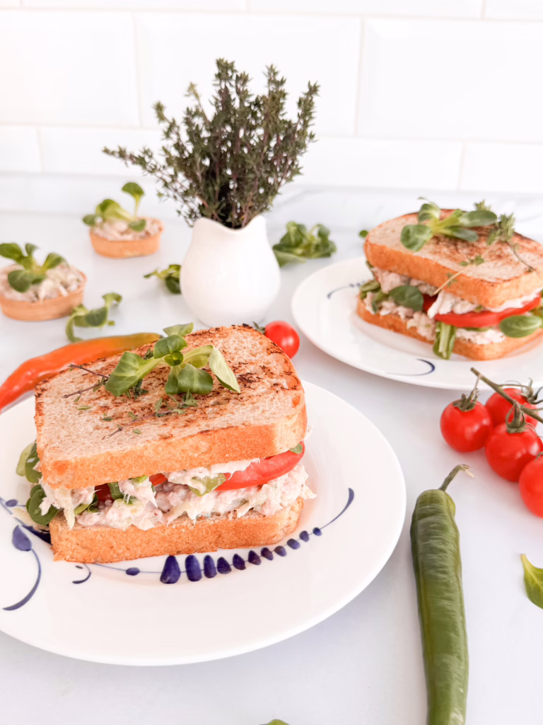 Апетитний клаб-сендвіч з тунцем, грушею та свіжим томатом на тарілці.