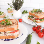 Апетитний клаб-сендвіч з тунцем, грушею та свіжим томатом на тарілці.