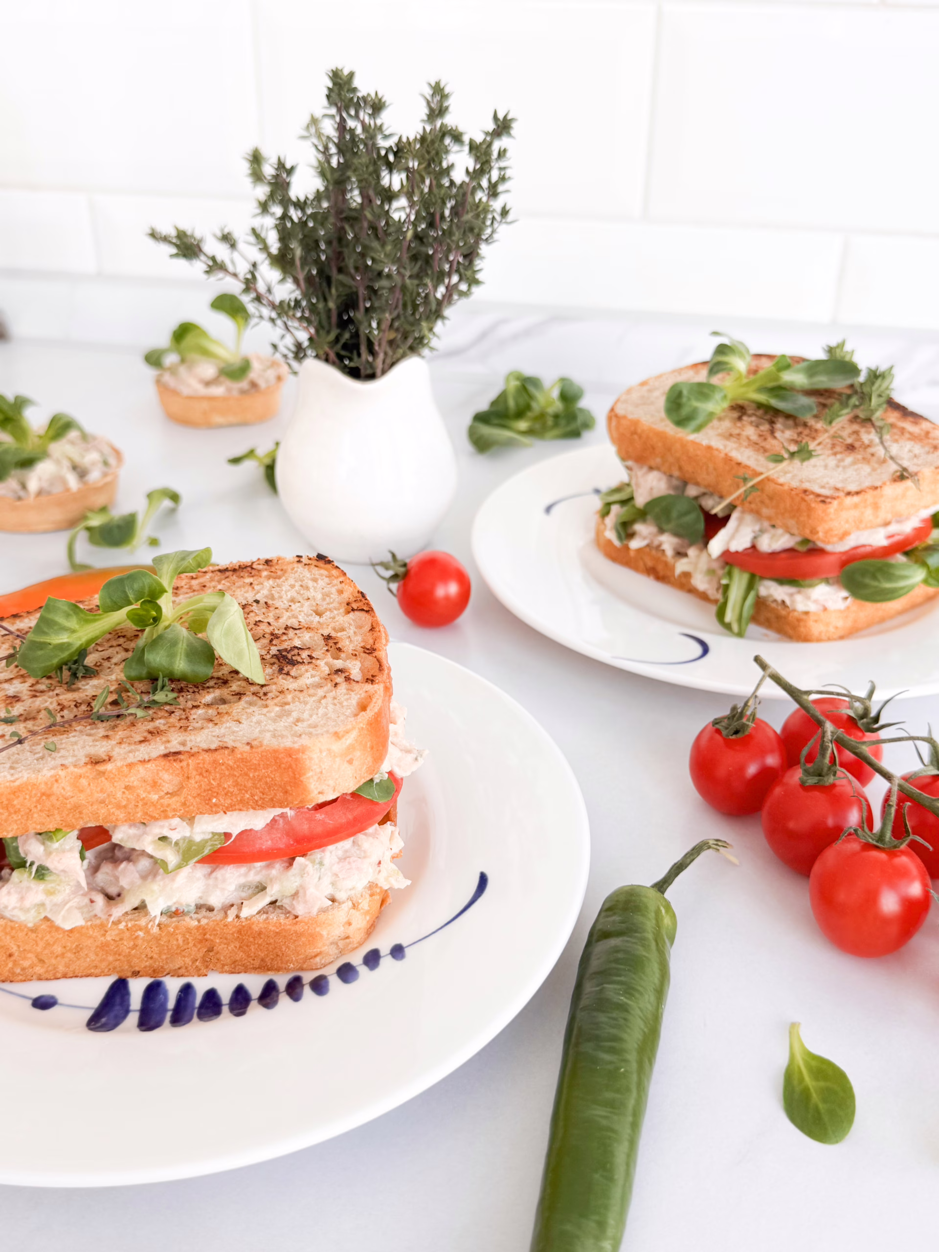 Апетитний клаб-сендвіч з тунцем, грушею та свіжим томатом на тарілці.