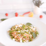 Тарілка апетитної пасти спагеті з яскравим зеленим горошком, цедрою лимона та пластівцями чилі, сервірована з кисломолочним сиром.