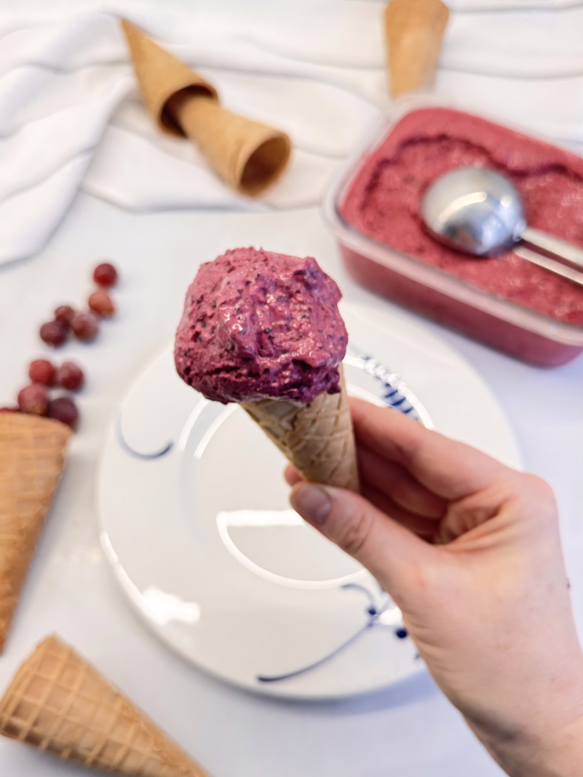 Густий ягідний фро-йо насиченого фіолетового кольору в красивій керамічній піалі, прикрашений свіжими ягодами та листочком м'яти.