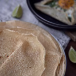 Апетитний бретонський креп із зеленої гречки, загорнутий конвертом на тарілці, з начинкою із розплавленого сиру, шпинату та томатів.