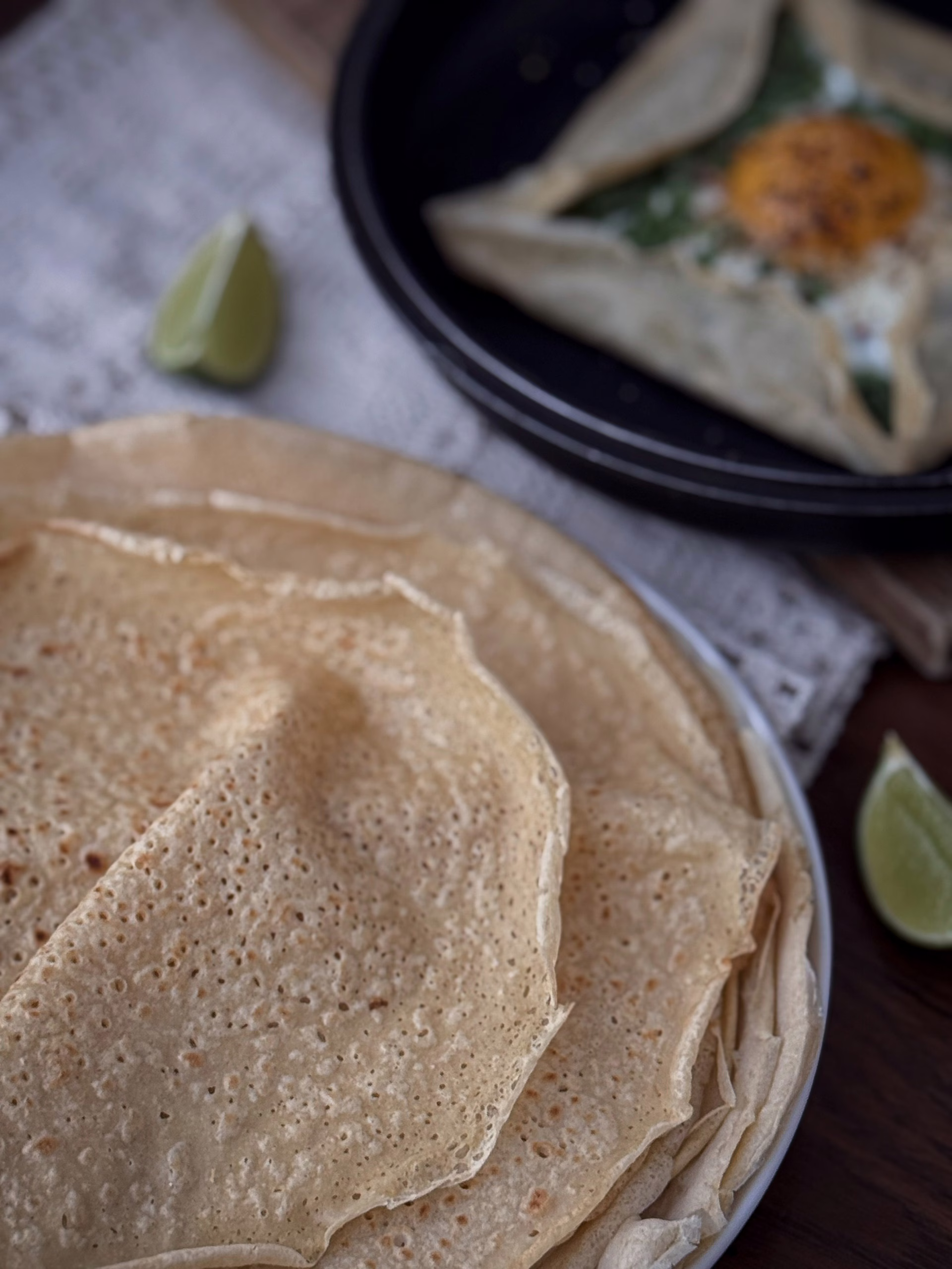 Апетитний бретонський креп із зеленої гречки, загорнутий конвертом на тарілці, з начинкою із розплавленого сиру, шпинату та томатів.