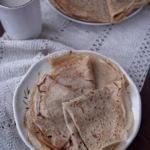 Тонкі, еластичні млинці з борошна зеленої гречки, апетитно згорнуті на тарілці, з золотистою скоринкою.