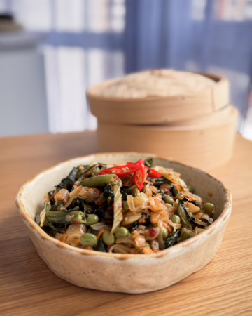 Тушкована селера з едамаме, фенхелем та чилі в матовій керамічній піалі. Естетичні рослинні рецепти українською від кулінарного журналу CookItTwice.