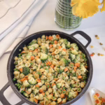 різнокольорова паста з зеленими овочами подана на чавунній пательні