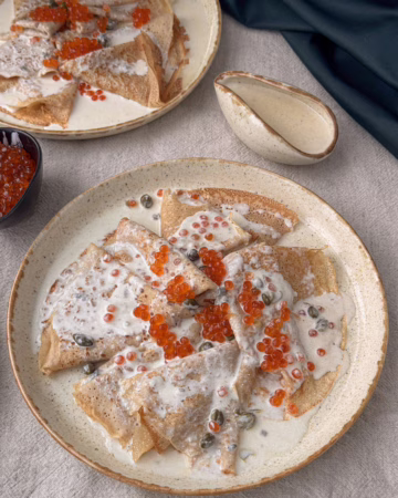 Сервірування безглютенових гречаних млинців із сирним соусом та червоною ікрою у вінтажній керамічній піалі, CookItTwice стиль. Еластичне тісто на млинці із зеленої гречки в процесі замішування.