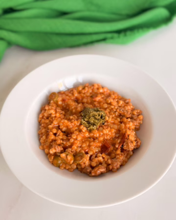 Сервірування гарячого птісото з м'ясом у білій глибокій керамічній тарілці, зверху ложка холодного песто, на фоні зелена лляна серветка, CookItTwice стиль.