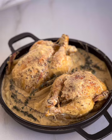 Золотисті запечені курчата у вершковому соусі на матовому керамічному блюді, сервірування у стилі тихої розкоші cookittwice.