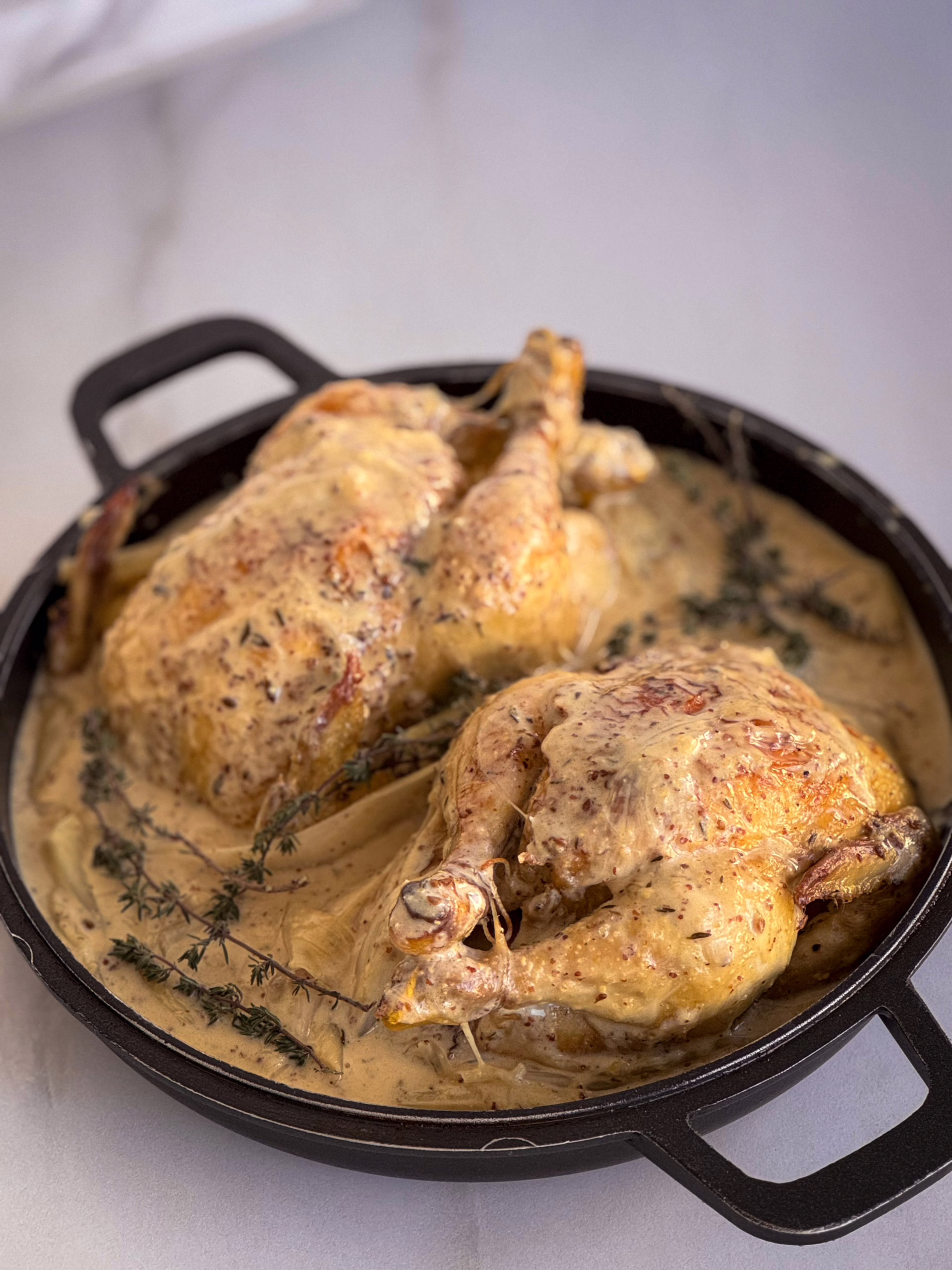 Золотисті запечені курчата у вершковому соусі на матовому керамічному блюді, сервірування у стилі тихої розкоші cookittwice.