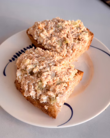 Сервірування намазки з тунця та сиру на підсмаженому хлібі у вінтажній тарілці з синім візерунком, CookItTwice стиль.