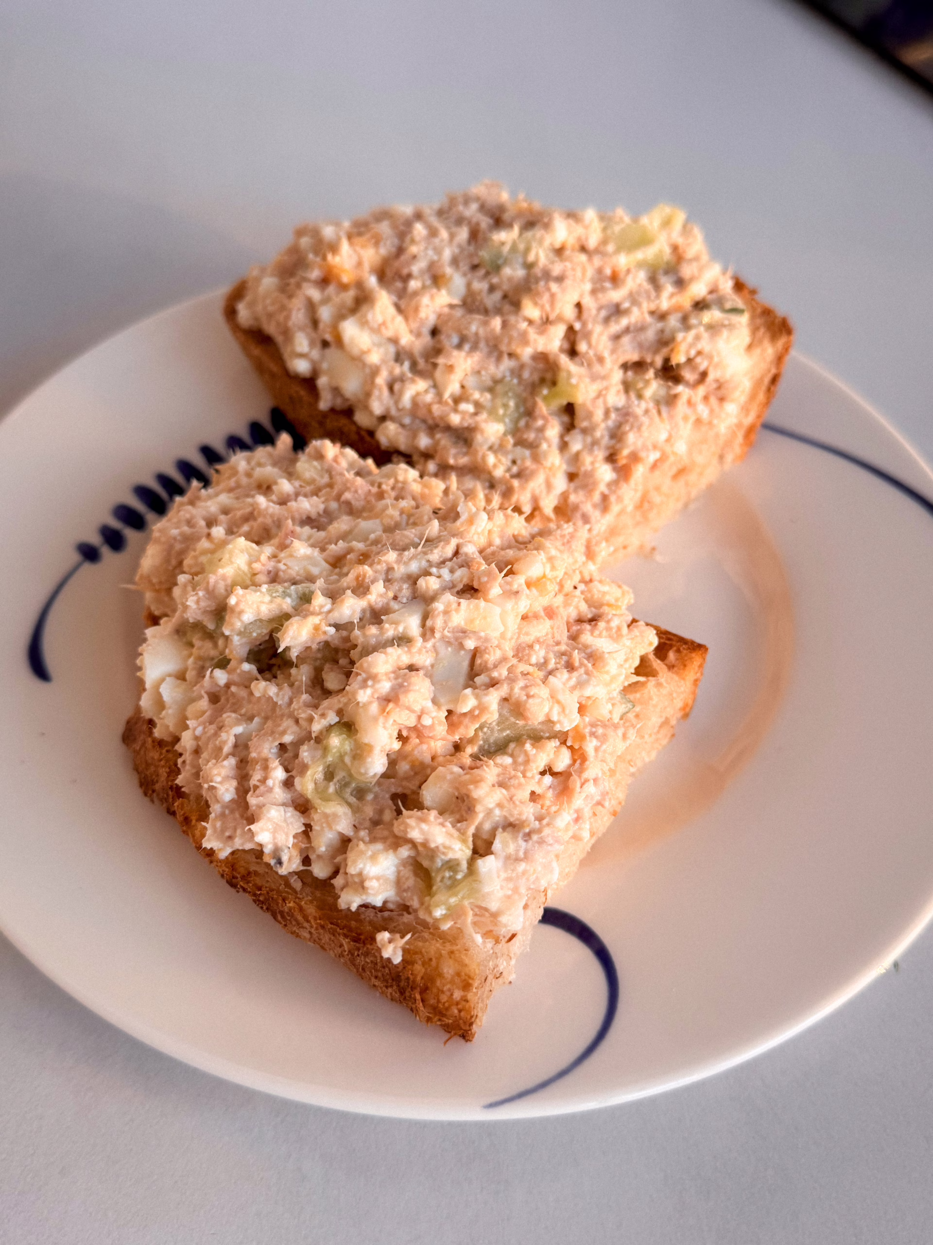 Сервірування намазки з тунця та сиру на підсмаженому хлібі у вінтажній тарілці з синім візерунком, CookItTwice стиль.