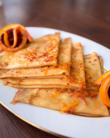 Сервірування гарячих млинців Креп Сюзетт у вінтажній тарілці з густими вершками, CookItTwice стиль.