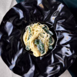 Сервірована на чорному блюді паста з лимоном та рікотою й шпинатом.