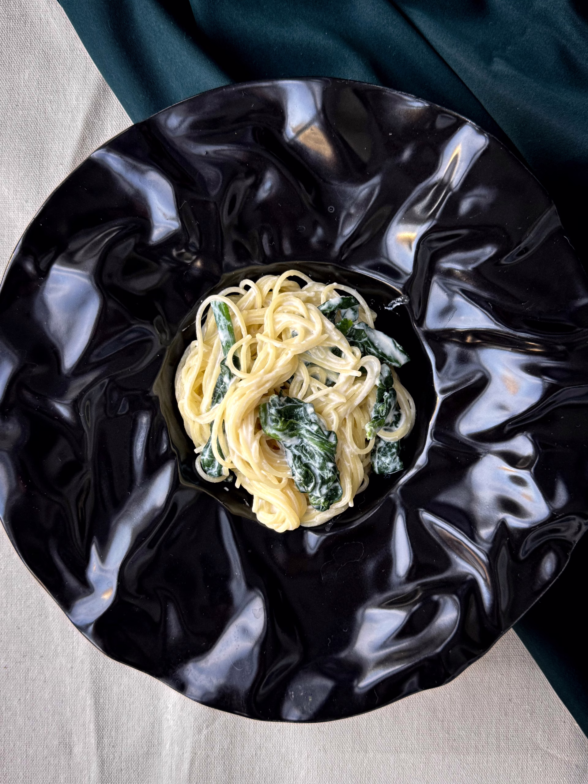 Сервірована на чорному блюді паста з лимоном та рікотою й шпинатом.