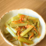 Томлена стеблова селера у глянцевій глазурі з морквою та цибулею у керамічній тарілці.