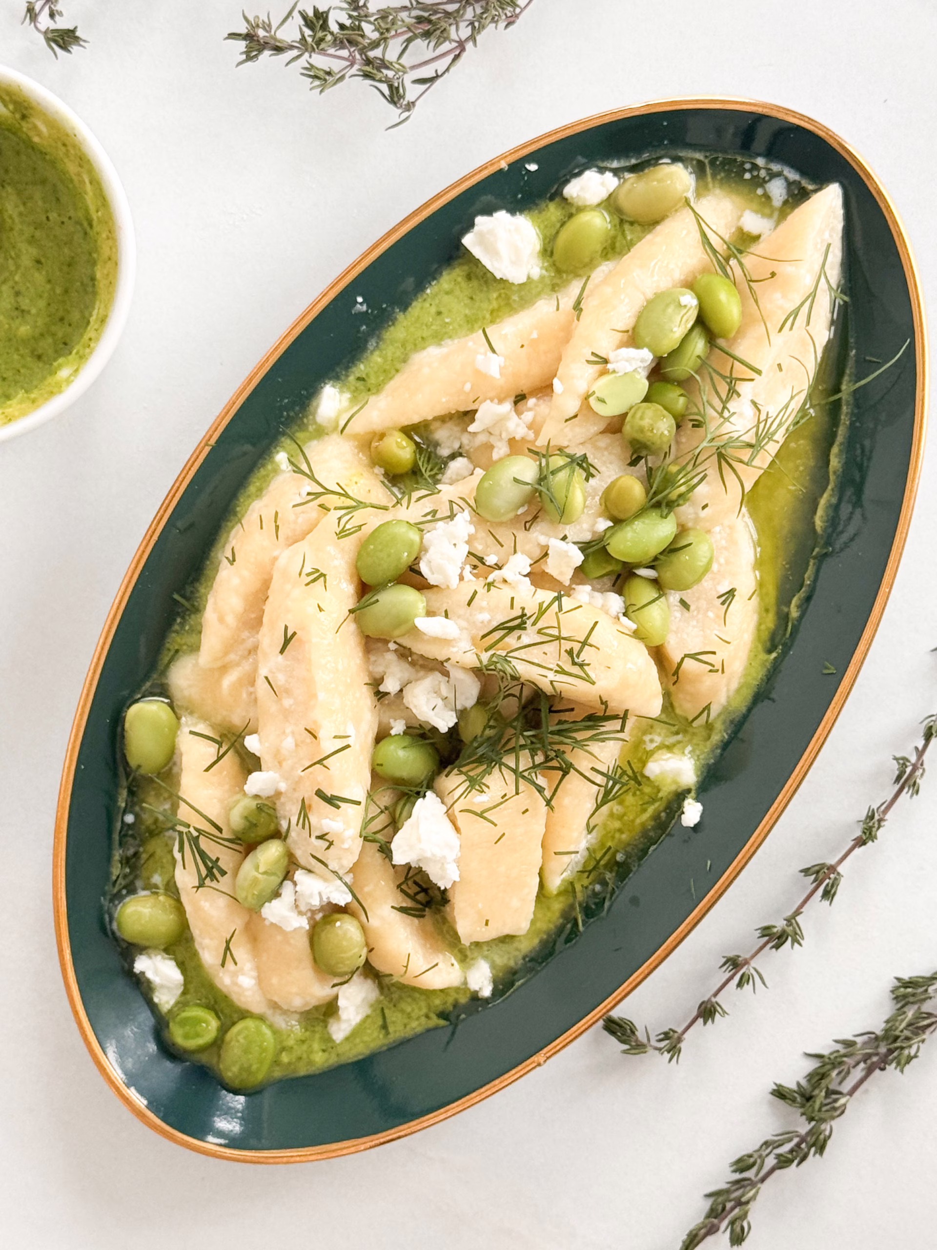 Готові ліниві вареники на смарагдовому соусі з горошку та едамаме у глибокій керамічній тарілці, CookItTwice стиль.