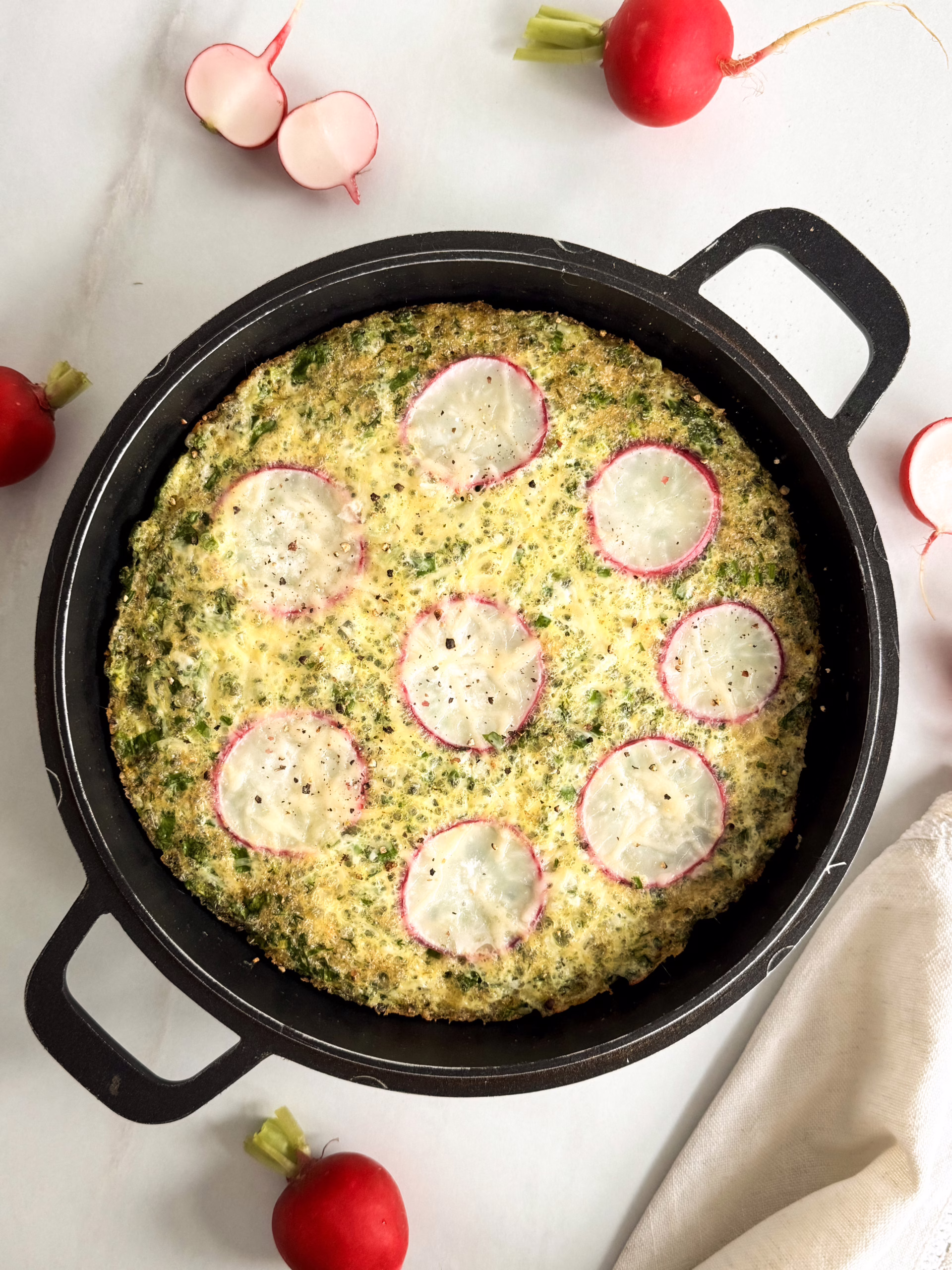 Запечений зелений омлет у чавунній сковороді з геометричним візерунком із 7 слайсів редису.