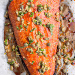 Запечене філе червоної риби на тарілці з зеленою сальсою. Соус із тахіні в піалі.