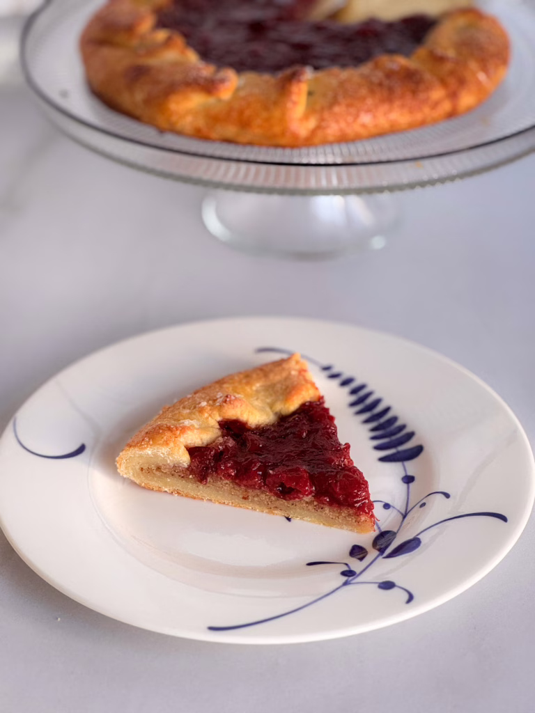 Шматок вишневої галети з глянцевою начинкою та горіховим франжипаном на керамічній тарілці