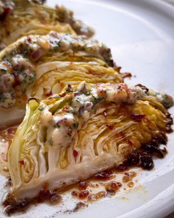 Запечені скибочки капусти на світлій тарілці; Збивання гірчичного соусу вінчиком; Нарізана зелена капуста на дерев'яній дошці.