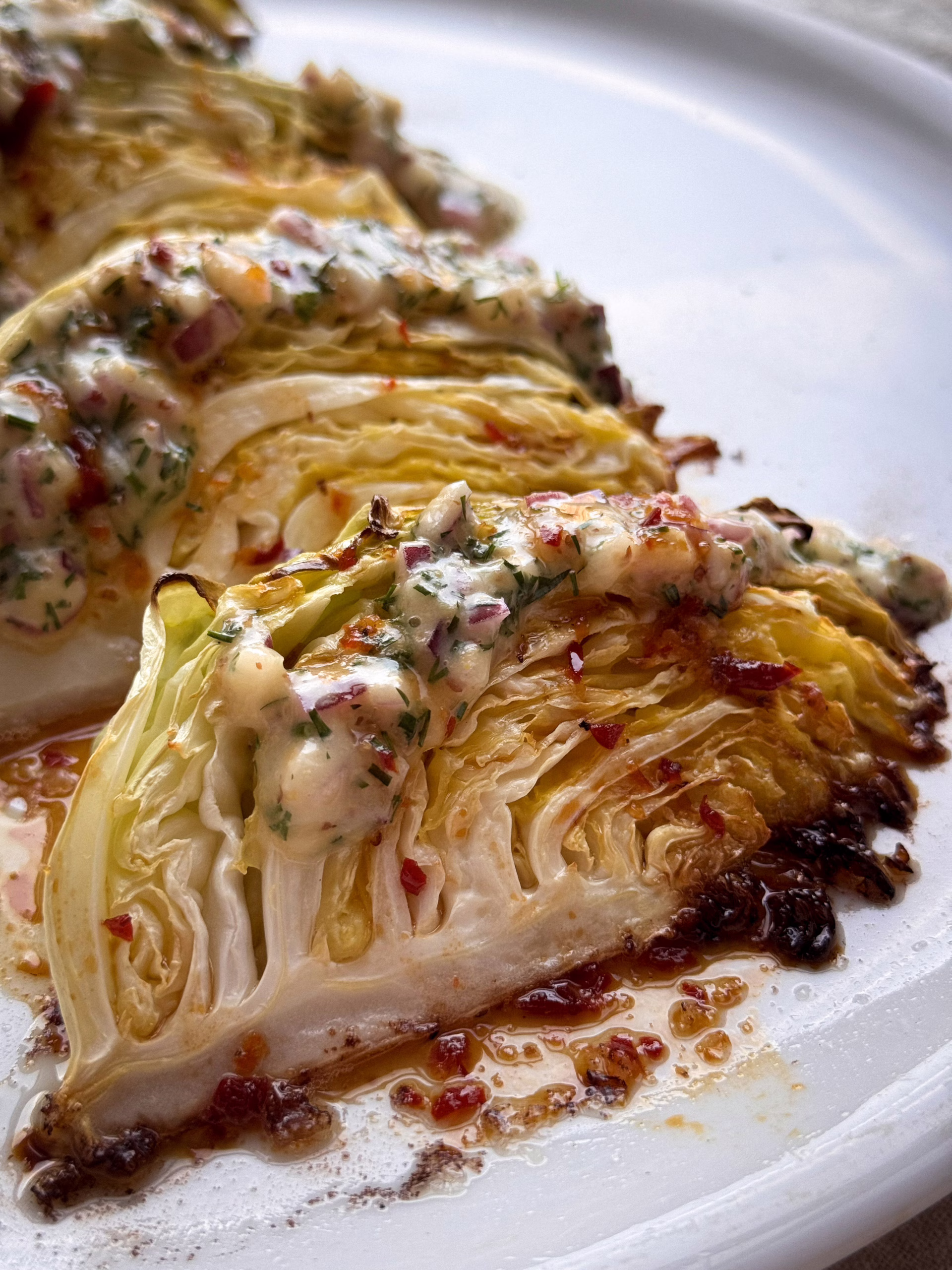 Запечені скибочки капусти на світлій тарілці; Збивання гірчичного соусу вінчиком; Нарізана зелена капуста на дерев'яній дошці.