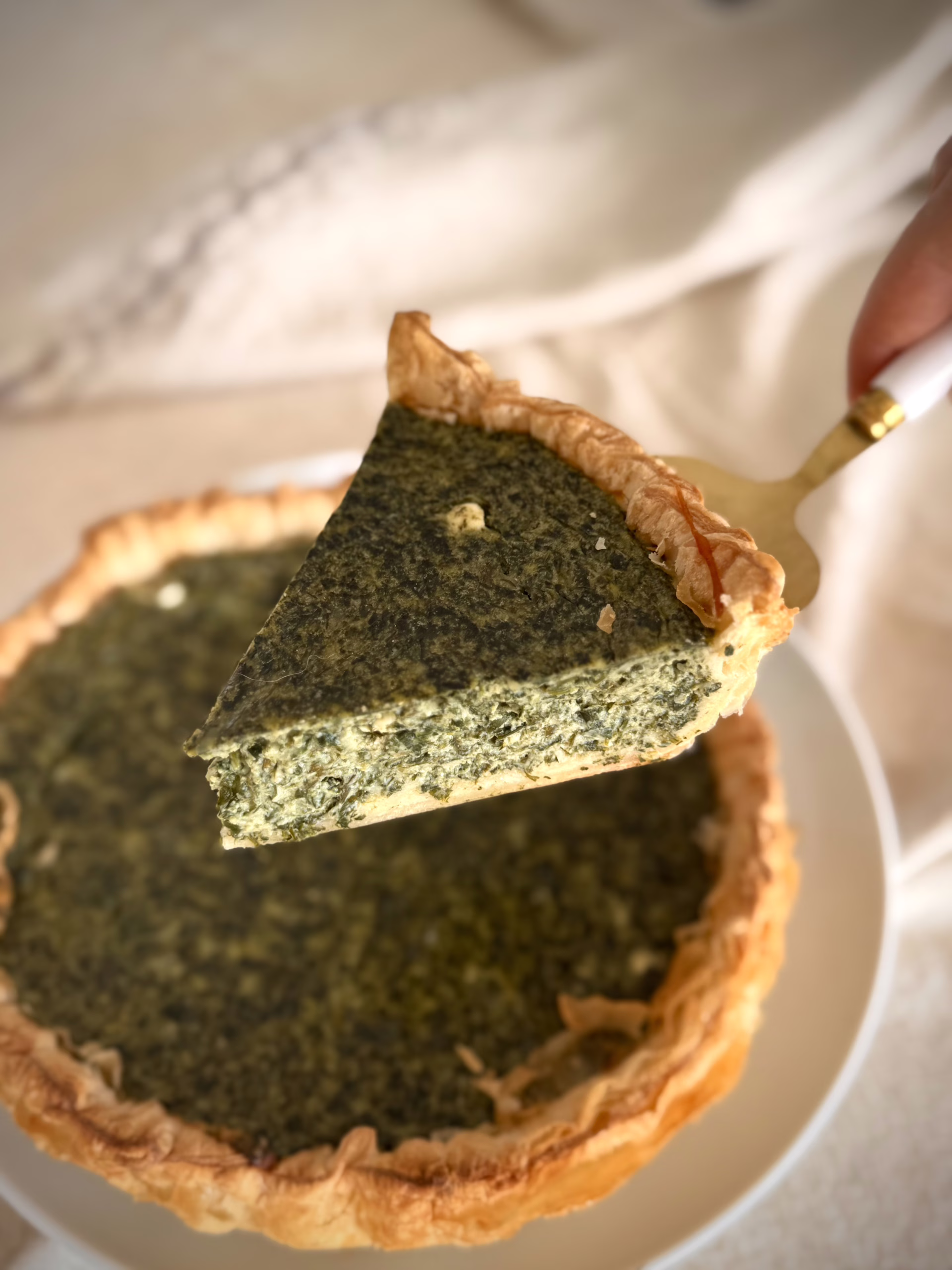 Золотистий кіш з зеленню на фоні лляної серветки, текстура рикоти зі шпинатом